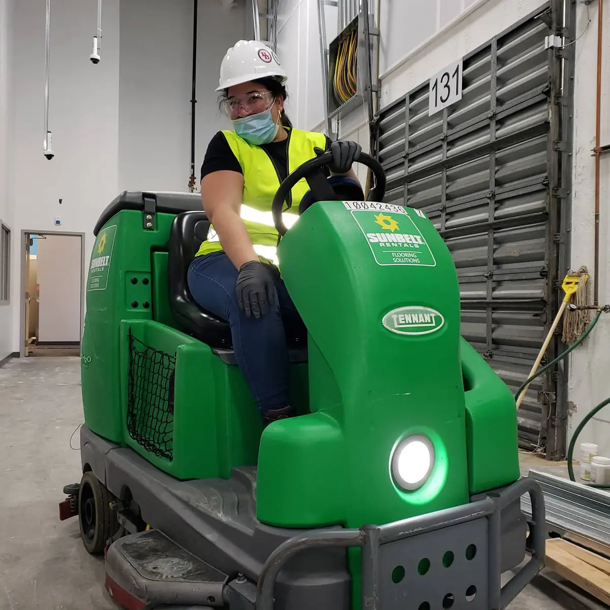 Miami Top Cleaning employee driving a ride-on floor scrubber in a warehouse